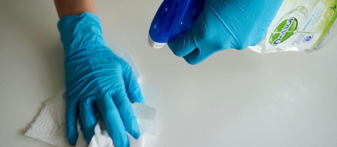 Gloved hands wiping a surface clean